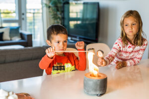 Unsupervised kids near open fire pit roasting marshmallows, emphasizing burn injury and fire safety risks